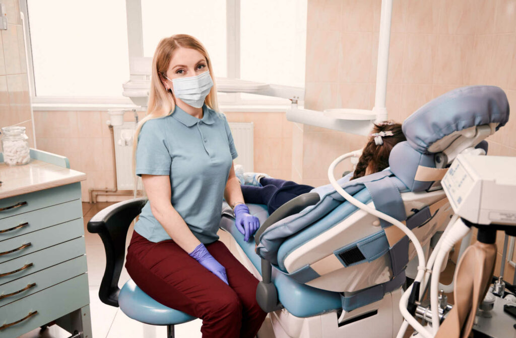 Female dentist sitting next to a dental chair with