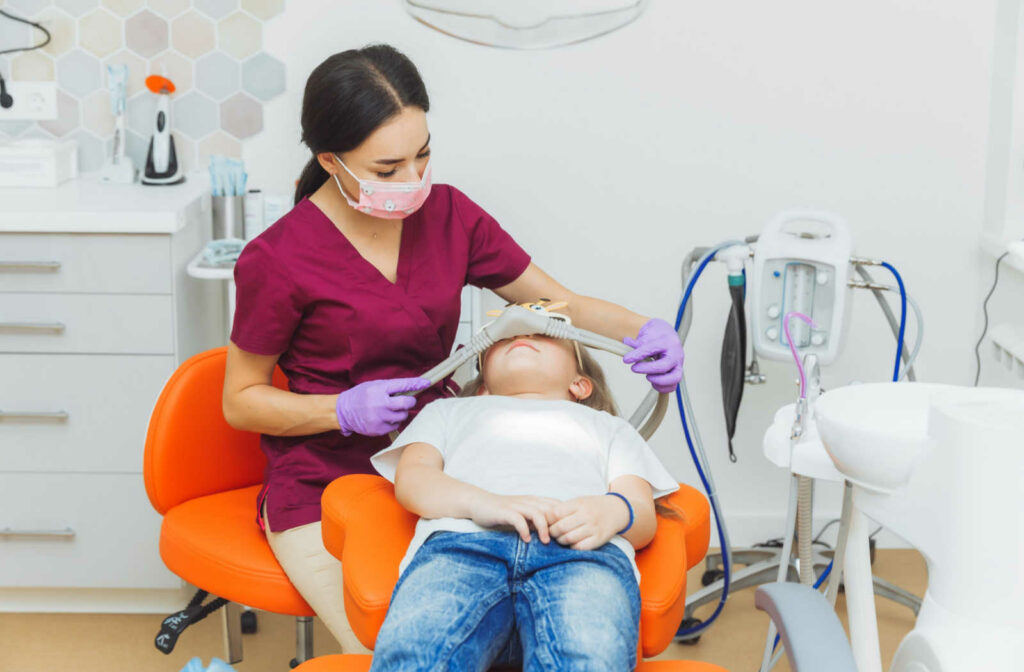 A female dentist placing the nitrous oxide mask onto a young patient.