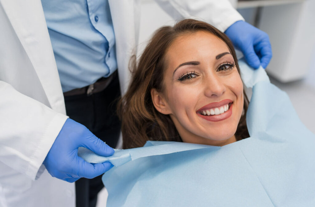 Close-up of a woman smiling while her dentist applies a dental bib